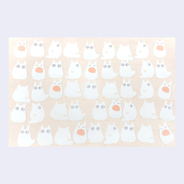 Sheet of white cartoon chibi Totoro characters with orange accents on a beige background
