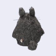 Dark gray Totoro plush, with a large white furry belly and whiskers. View from the back, with a small tail.