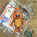 Cartoon character keychain in clear packaging on a textured surface