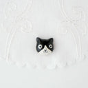 3D ceramic brooch/pin of a tuxedo cat's head, with a simple and cute cartoon smile.