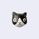 3D ceramic brooch/pin of a tuxedo cat's head, with a simple and cute cartoon smile.