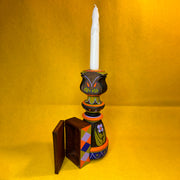 Decorative candle holder with a white candle on a yellow background