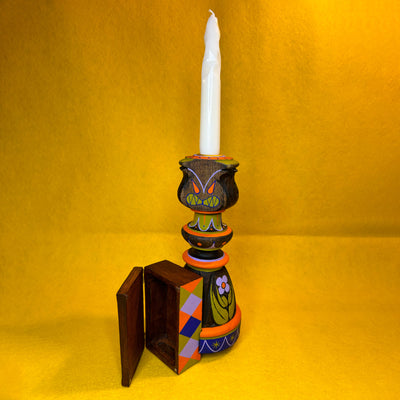 Decorative candle holder with a white candle on a yellow background