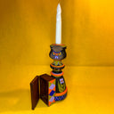 Decorative candle holder with a white candle on a yellow background