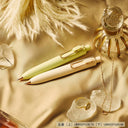 Two pens on a textured surface with crystals and a ring.