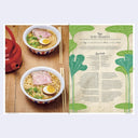 Bowl of Shio Ramen with a red teapot on a wooden surface, next to a recipe card.