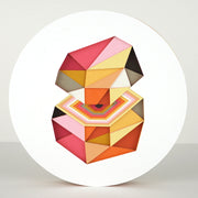 Geometric designed layered cut paper sculpture, creating a three dimensionality. A 10 sided shape is cut horizontally, revealing a hexagonal interior. Colors are orange, brown, yellow, pink and white.