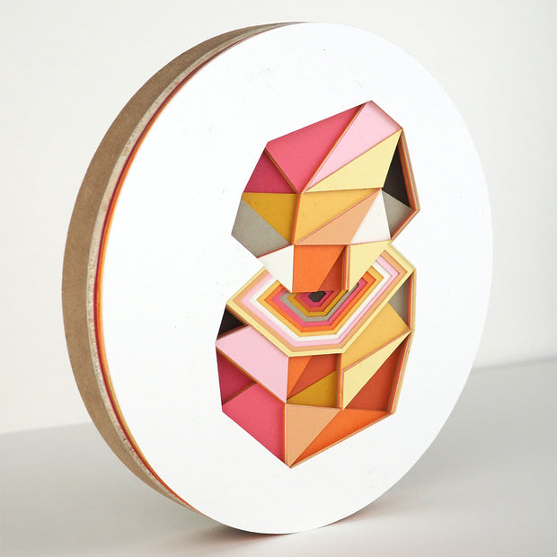 Geometric designed layered cut paper sculpture, creating a three dimensionality. A 10 sided shape is cut horizontally, revealing a hexagonal interior. Colors are orange, brown, yellow, pink and white.