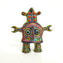 Colorful clay figure made to look like a toy robot of sorts, covered in very intricate design patterns with 2 eyes in the center.