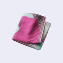Folded fabric with pink, green, and gray patterns on a light purple background