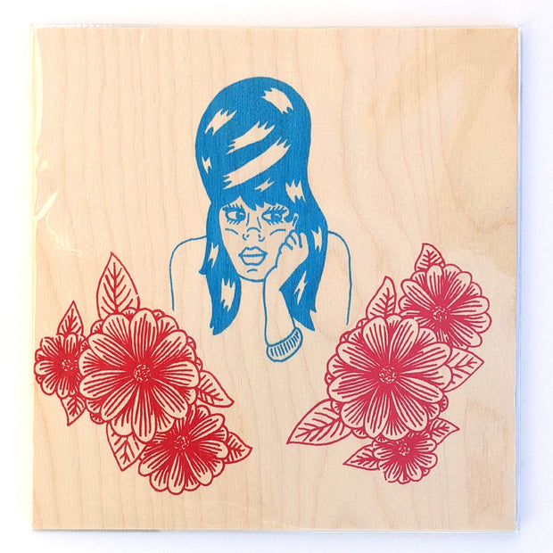 Screenprint on wood of a blue cartoon style woman with tall hair and her hand resting on her cheek. Framing her are red flower bunches.