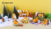 Display of each option for Woow Tiger blind box figures. Options are: snowman, getting groceries, fish hats, lucky cats, lounging with books, tiger in box, cheeseburger, exercise and eating cookies.