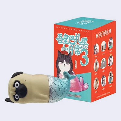 Toy figure of a pug in a mermaid tail, leaning on its side in front of its product packaging.