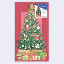 A Christmas-themed greeting card featuring a large illustrated green Christmas tree with ornaments, Santa Claus figures, gifts, and a gold star on a red background. A small insert in the top right shows a smaller tree and Japanese text.