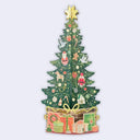 A 3D pop-up cardboard Christmas tree decoration on a light gray background. The green tree is decorated with various colorful holiday ornaments, a gold star topper, and sits in a base of wrapped presents with a gold bow.