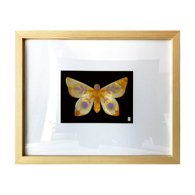Painting on cut out paper of a butterfly with orange, yellow and purple coloring. Its wings are mostly tipped with orange glitter and have purple circle and leave patterns on the rest of the wing. Butterfly is mounted on black paper and in a light grain wooden frame.