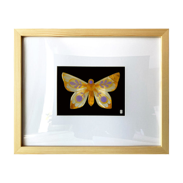 Painting on cut out paper of a butterfly with orange, yellow and purple coloring. Its wings are mostly tipped with orange glitter and have purple circle and leave patterns on the rest of the wing. Butterfly is mounted on black paper and in a light grain wooden frame.