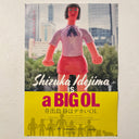 Faux movie poster for "Shizuka Idejima is a BIG OL" featuring posed vinyl figures in a scene, a large woman dressed in office wear stands in a city.