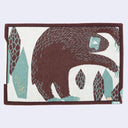 Rectangular fabric placemat with an illustration of a blue snow yeti, standing on its hind legs and bent to the side, as if in the middle of a side stretch. It stands near geometric rock shards. Back view so colors are inverted.