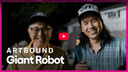 Two men wearing hats with text, one holding a microphone, against a dark background with 'Artbound Giant Robot' branding.