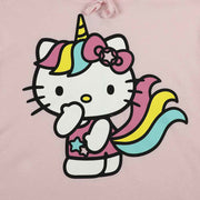 Close up graphic of Hello Kitty standing, with one hand touching her face. She has a rainbow unicorn mane that runs down to her tail and a unicorn horn. She wears pink overalls with blue and light pink stars.