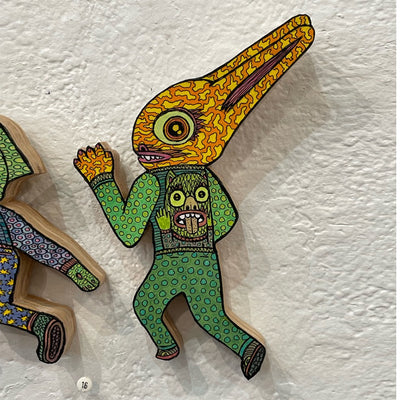 Illustrated wood cut rabbit-like monster, positioned as if running away. It wears green polka dot long sleeve and pants, with a striped sweater with an illustration of a monster on the back. 