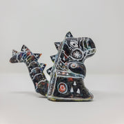 A small sculpture of a primarily black Godzilla, with peeks of rainbow color coming out in place. It has many white lines depicting various robotic elements.