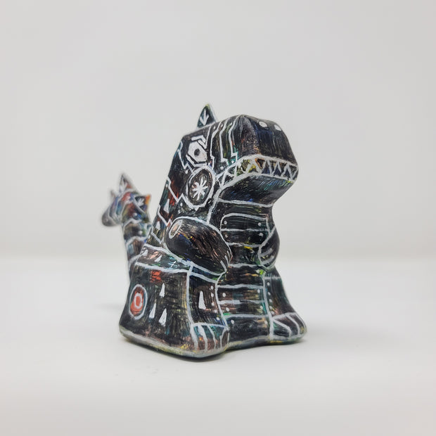 Side view of a small sculpture of a primarily black Godzilla, with peeks of rainbow color coming out in place. It has many white lines depicting various robotic elements.