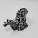 Back view of a small sculpture of a primarily black Godzilla, with peeks of rainbow color coming out in place. It has many white lines depicting various robotic elements.