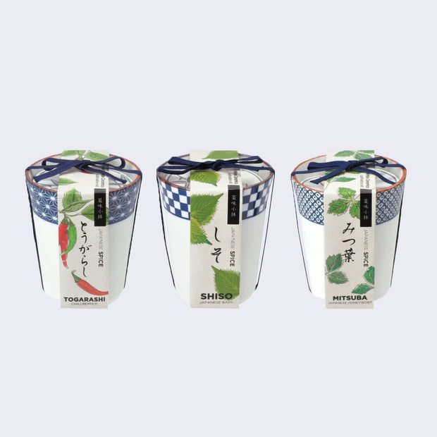 3 white ceramic cups, with blue patterning around the rim. Each has its own paper label and a blue string, bundling the label to the cup. Labels read: Togarashi, Shiso and Mitsuba.