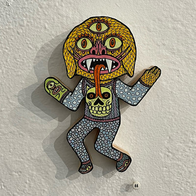 Illustrated wood cut of yellow goblin with three eyes, wearing a sweater vest with a skull. It wears a hand mitt designed as a monster.