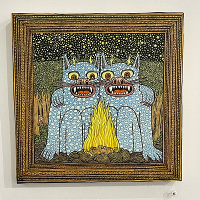 Illustration on wood with a thick patterned border. Two cat-like monsters sit together in front of a campfire with arms wrapped over each other.