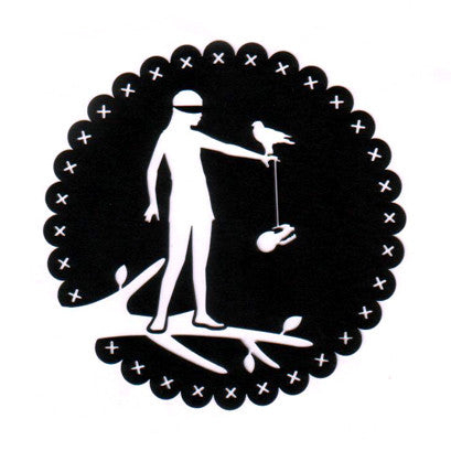 Black circular paper cutting of a person with a blindfold standing on a single branch, a bird resting on their arm and an animal skull hanging from a string.