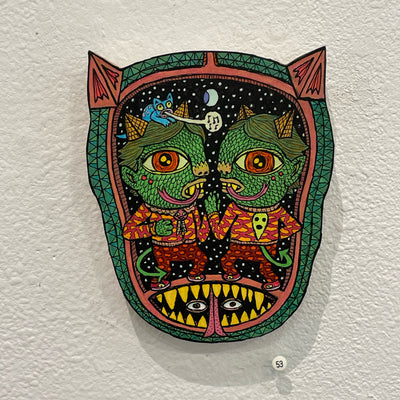 Illustrated wood cut of a goblin head, with two green goblins inside wearing matching patterned outfits and pyramid heads.