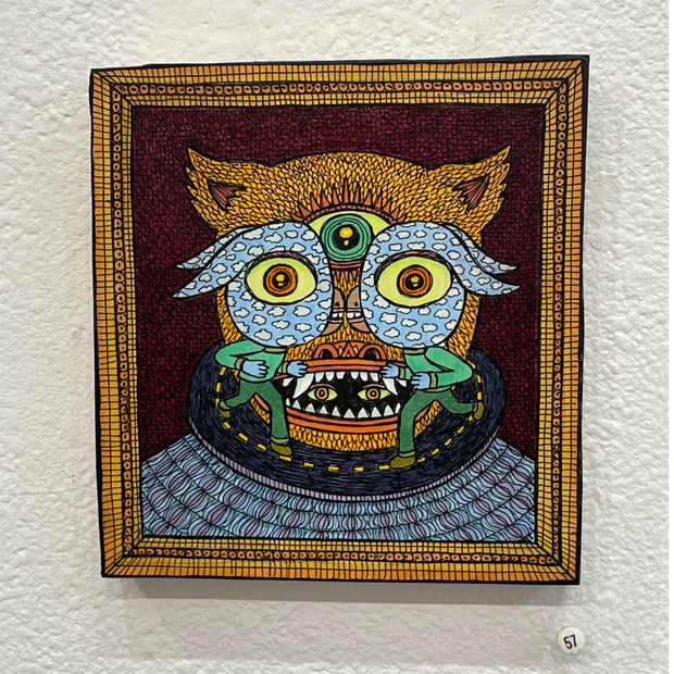 Illustration on wood of a cat eared goblin with a circular road around its neck wearing a patterned sweater. 2 matching bird like goblins stand on the road in front of the goblin's face.
