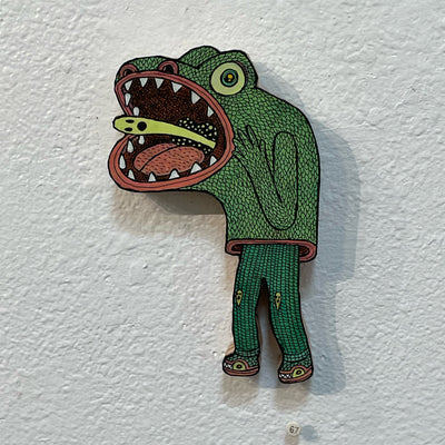 Illustrated wood cut of a frog headed creature with a large open mouth and a small green ghost coming up out of its throat.