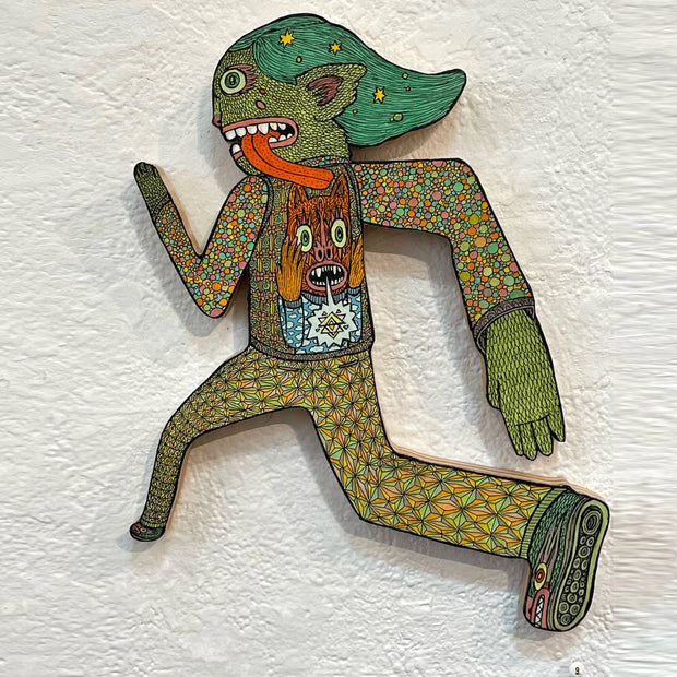 Illustrated wood cut figure of a green goblin with mid length green hair with yellow stars, mid stride as if running. Goblin has a long red tongue and wears a patterned sweater and pants. A monster with its hands on its face is on the goblin's back like a backpack.