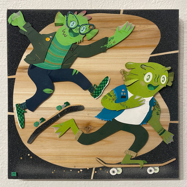 Stylized cartoon paper cut illustration of two green smiling sea monster creatures riding on skateboards, one doing a kick flip and the other pushing its board.