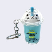 Keychain attached to a clear to go cup container with blue liquid, boba at the bottom and whipped cream on top that is shaped like a kawaii cat, with a blue straw coming through the top.