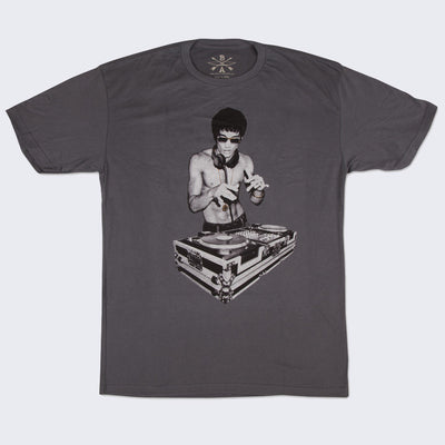 Front side of dark gray t-shirt. Black and white photo of Bruce Lee using a DJ turntable. He wears a long gold necklace and dark sunglasses.