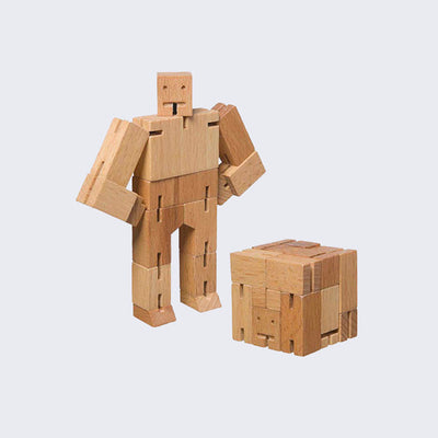 Wooden robot made of square-like shapes, standing with both arms on its hips. In front is the same robot, folded into the shape of a perfect cube.