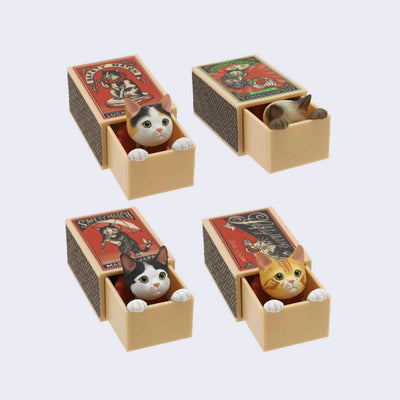 4 variations of a small vinyl sculpt of a cat inside of a wooden matchbox, with vintage imagery of cats on the top. Its paws sit on the edge of the matchbox. Cats options are: calico, Siamese, white with black spots, and orange tabby cat.