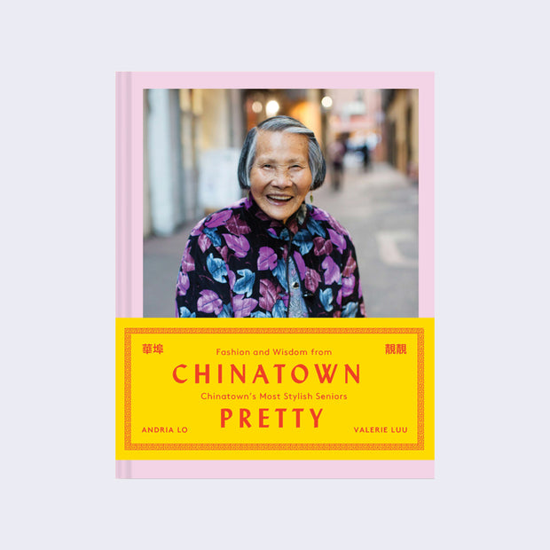 Pink hardcover book featuring a photograph of a smiling elderly Asian woman, wearing a black coat with bright purple and blue florals. A block of yellow features text, "Chinatown Pretty: Fashion and Wisdom from Chinatown's Most Stylish Seniors"