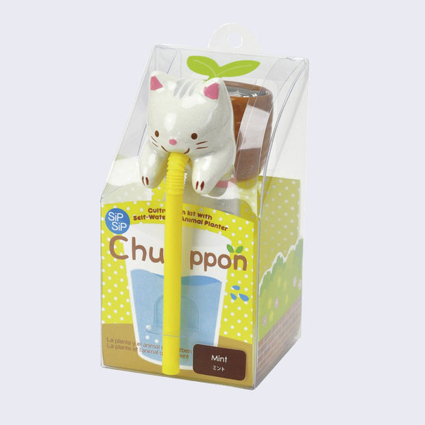 White ceramic cat with a small brown pot on its back, drinking out of a long yellow straw, encased in plastic packaging that has a yellow polka dot wrap with an illustration of a water cup. "Chuppon" is written above the cup.