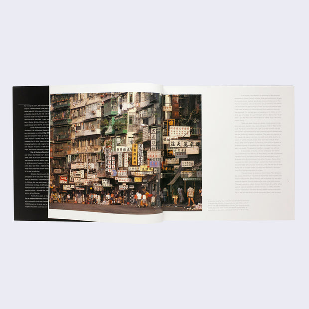Open two page book spread. Photograph of a incredibly busy urban setting, with many Chinese signs and stacked apartment buildings. Informational text accompanies photo.