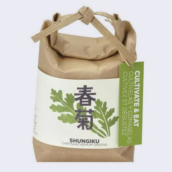  Brown paper sack, folded and tied with a paper tie and a green hang tag that reads "Cultivate & Eat". Wrapped around is a cream sheet, with an illustration of chrysanthemum greens and Japanese script in the middle. "Shungiku Chrysanthemum Greens" is written on the bottom.