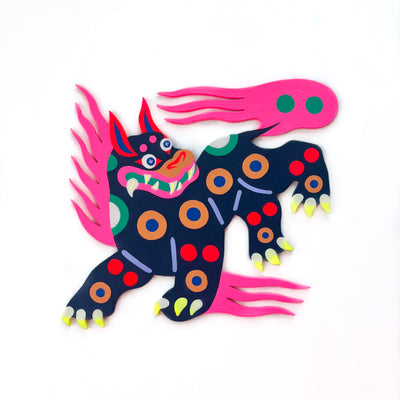 Die cut, brightly painted wooden sculpture of an old folklore style dragon dog, navy blue with colorful polka dots and a large pink mane.