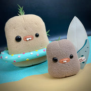 Set of 2 plush potatoes, one light brown and the other smaller and medium brown. They have mismatched eyes, buckteeth and sprouts growing from their heads. Larger one has a pool ring floaty and the baby has a surfboard.