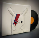 Vinyl (pleather) recreation of David Bowie's "Aladdin Sane" vinyl record cover, with a white bunny in the center instead of David Bowie. The bunny has lightning bolts of red and blue over its left eye. A pleather record peeps out from the album cover.