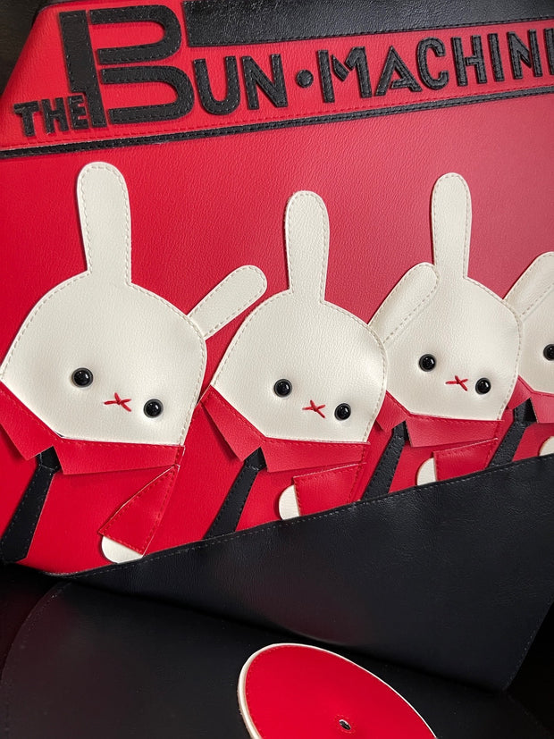  Vinyl (pleather) recreation of Kraftwerk's "The Man Machine" album cover, with a pleather album peeping out from the vinyl sleeve. Cover features 3 white bunnies, wearing matching red button ups and black ties with "The Bun Machine" written in black stylized font on a red background.
